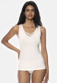 Light beige tank top with wide straps, a V-neck, and lace trim. Soft fabric with a smooth texture, designed for a fitted look.