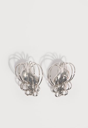 Ezüst fém fülbevaló pár, nyitott huzal ketrec kialakítással és sima, központi ovális formákkal, amelyek ívelt árnyékokat vetnek fehér háttéren.