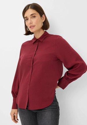 Bordeaux lange mouwen blouse met een knoopsluiting aan de voorkant, kraag en ronde zoom. Zachte stof met een gladde textuur, voorzien van knoopmansetten.