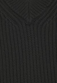 Tmavě šedá pletená látka s ribbovým vzorem tvořícím chevronový design blízko horního středu.