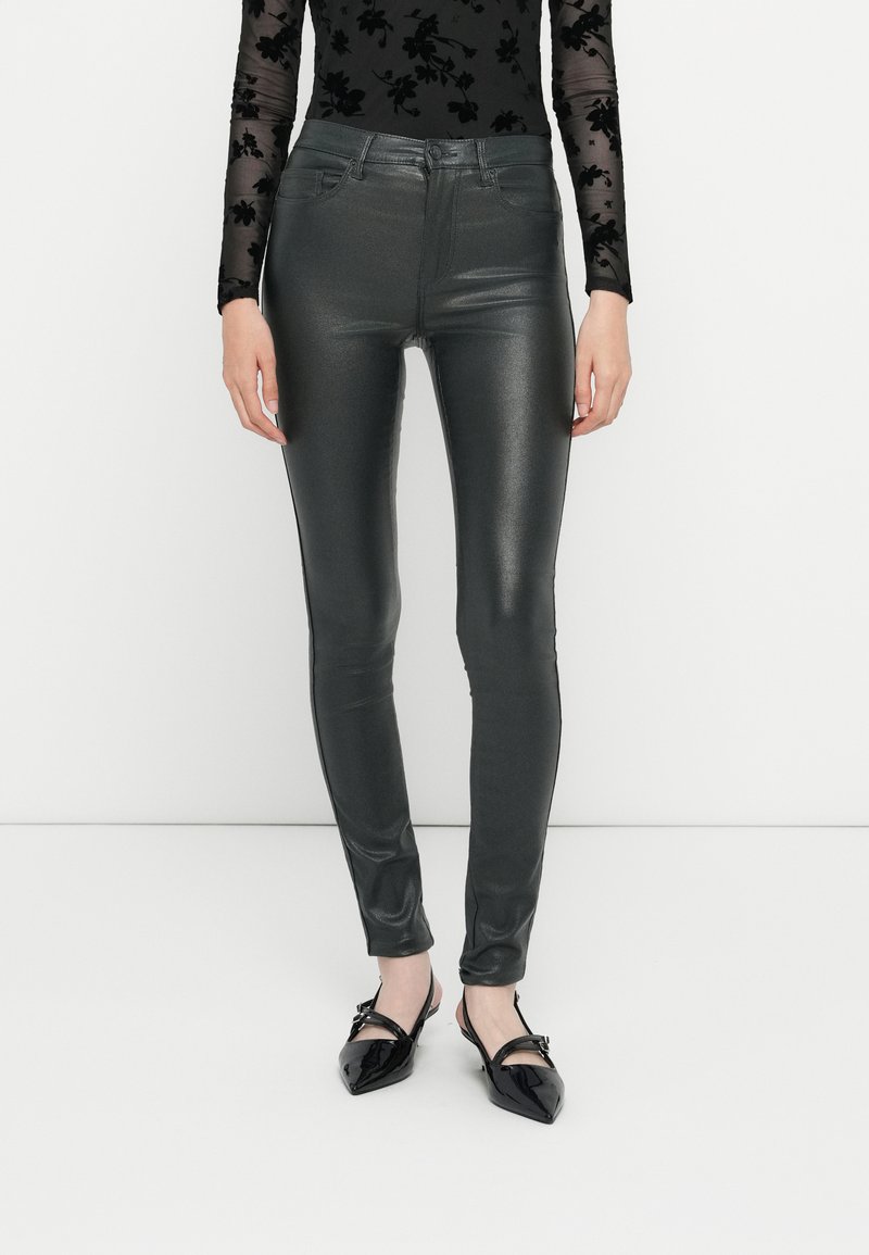 Υψηλόμεσα, μεταλλικά γκρι στενά παντελόνια με λεία, λαμπερή υφή· διαθέτουν εμπρόσθιες τσέπες και κλείσιμο με φερμουάρ.