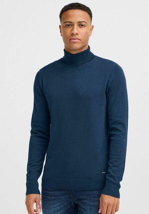 Navy turtleneck sweater made of soft, stretchable fabric. Long sleeves with ribbed cuffs and hem. Minimal branding detail at the lower side.