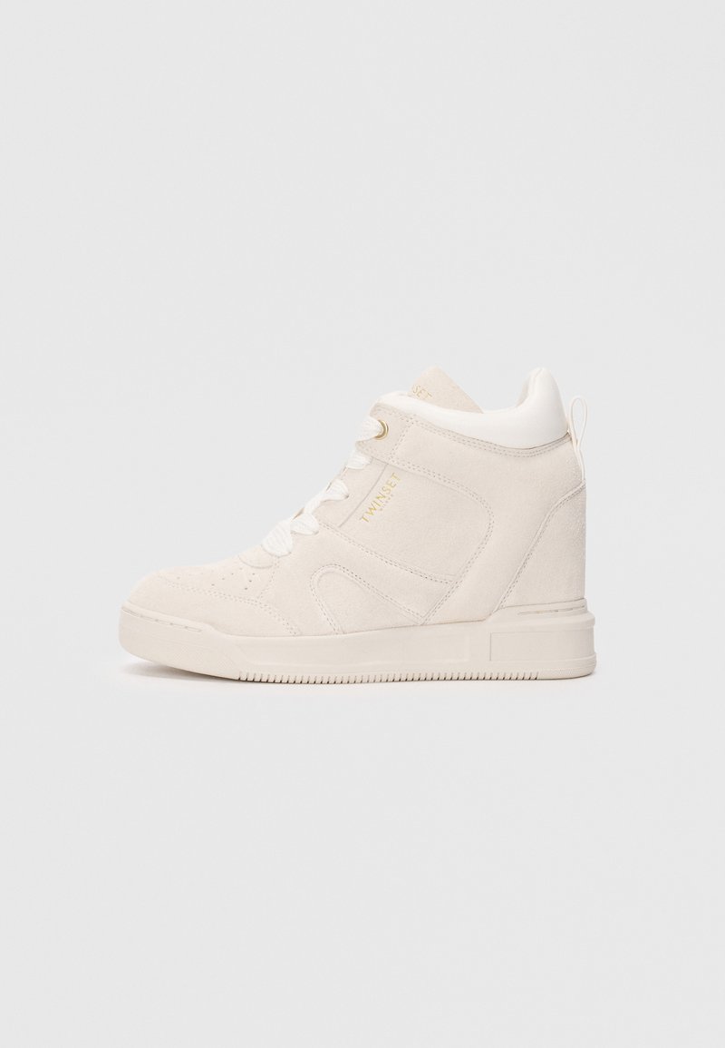 Hochschuh aus weichem Creme-Suede mit strukturierter Oberfläche. Verfügt über weiße Schnürsenkel, goldene Logos und eine klobige Sohle.