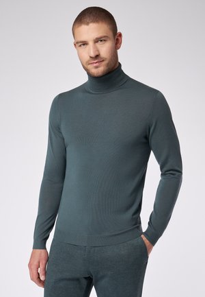 Donkerblauwe coltrui in een geribbelde textuur, met lange mouwen en een aansluitende pasvorm. Gecombineerd met bijpassende textuurbroek.