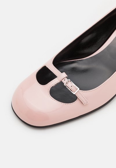 Ballet flat in pelle verniciata rosa con punta aperta e una fibbia decorativa. L'interno presenta una fodera nera liscia.