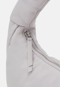 Helllila Ledertasche mit weicher, abgerundeter Form. Verfügt über einen sichtbaren Reißverschluss und Tab-Detail, das eine strukturierte, glatte Oberfläche zeigt.