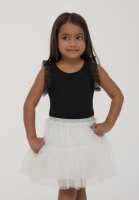 Body nero con maniche trasparenti a volant, abbinato a una gonna di tulle bianca con finitura glitter e vita elastica.