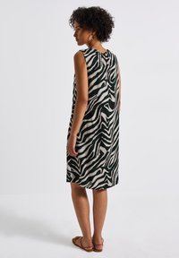 Ärmlös klänning med zebramönster, med en mörkgrön bas och vita ränder, lätt material och en detalj för stängning bak.