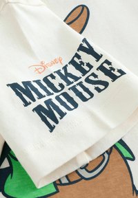 Hvid bomulds T-shirt med "Mickey Mouse" i fed marineblå tekst, med orange "Disney" logo og tegneseriefigur printdesign.