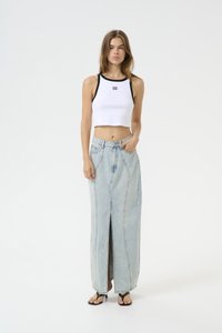 Hvitt ribbet crop top med svart halskant, parret med en lys blå denim maxi skjørt med splitt foran og lommer. Sorte flip-flops.