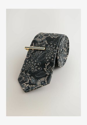 Dunkelblau gemusterte Krawatte aus strukturiertem Stoff, gerollt mit einem goldfarbenen Krawattenclip im rechteckigen Design.