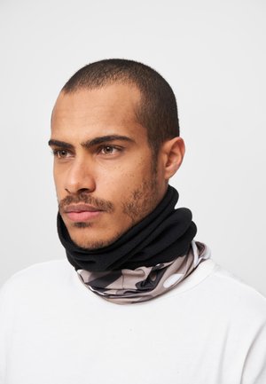 Il gaiter da collo multifunzionale presenta una sezione in pile nero e un tessuto decorato con punti beige e neri. Texture morbida, design tubolare.