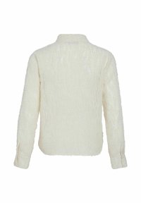 Camisa de color crema, de manga larga y con cuello. Tejido texturizado y suave con un patrón sutil. Presenta puños con botones y un dobladillo recto.