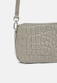 Borsa a tracolla in pelle grigia, testurizzata, con motivo coccodrillo, accessori in argento e tracolla rimovibile. Logo impresso sul davanti.