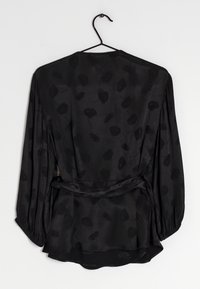 Zwarte blouse met lange mouwen en een wikkelontwerp, gemaakt van een glad materiaal, met subtiele bloemenpatronen en een gestrikte taille.