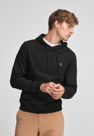 Zwarte hoodie gemaakt van een zacht materiaal, met een voorvak, verstelbare trekkoorden en een klein wit logo op de borst.