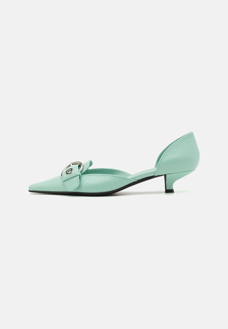 Mocasines de piel verde menta tipo slingback con punta afilada, pequeño tacón y detalle decorativo de hebilla. Textura suave con un brillo sutil.