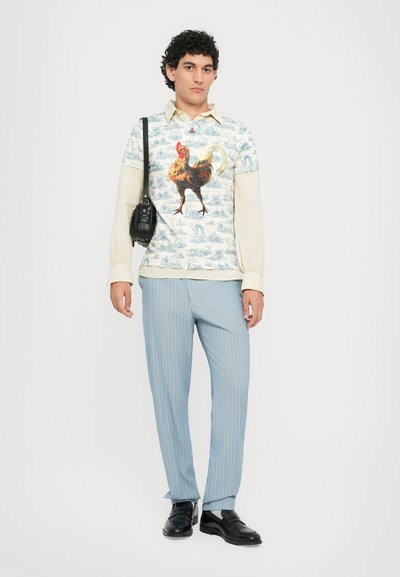 Camisa de manga larga con gráfico de gallo en tonos azules y crema, combinada con pantalones de rayas azul claro y mocasines negros.