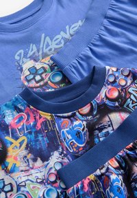 Blaue Grafik-T-Shirts mit lebendigen, bunten Designs und Motiven aus Videospielen, gerippten Kragen und unterschiedlichen Texturen.