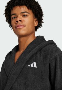 Black terrycloth bathrobe with a hood, featuring a white embroidered logo on the chest. Soft texture with a classic design.