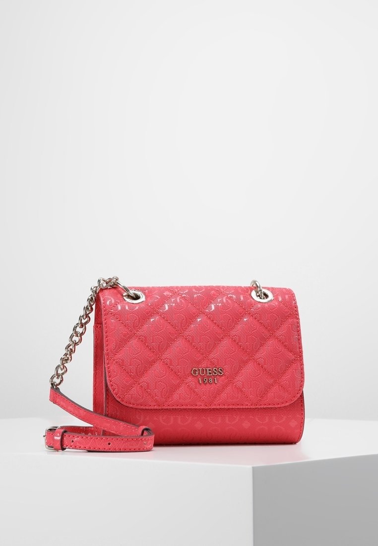 Růžová prošívaná kabelka z lakované kůže se stříbrným řetízkovým popruhem a logovými doplňky. Má klopnové zapínání s označením značky.