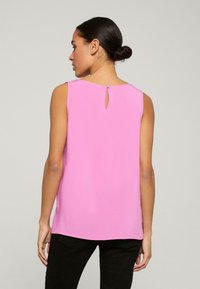 Mouwloos roze top met een keyhole rugdetail, gemaakt van lichte stof, met een eenvoudig ontwerp en rechte snit.