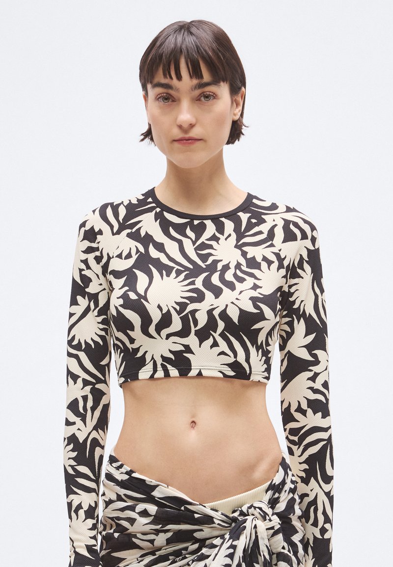 Κοντό τοπ με μακριά μανίκια, με μαύρο και κρεμ αφαίρετο λουλουδένιο μοτίβο, εφαρμοστό σχέδιο και υφή υφάσματος.