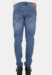 Jeans da uomo in denim blu con vestibilità a gamba dritta, dotati di due tasche posteriori e di una toppa in pelle color cuoio sulla cintura.