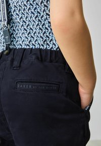 Sötétkék nadrág, rugalmas derékkal, varrt logóval, amelyen az "BAKER by TED BAKER" felirat olvasható, texturált anyagú, hátsó zsebbel.