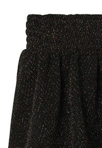 Jupe noire avec ceinture élastique, présentant un design texturé agrémenté de fils métalliques multicolores créant un effet de scintillement subtil.