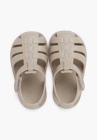 Beige plastikust sandaalid avatud varvaste disainiga, mitme horisontaalse rihmaga, tagarihmaga ja tekstuuriga sisetalla, millel on keerise muster.