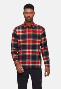 Camicia in flanella a quadri rossi e neri con accenti grigi, maniche lunghe, colletto chiuso da bottoni e una tasca sul petto con un piccolo logo.