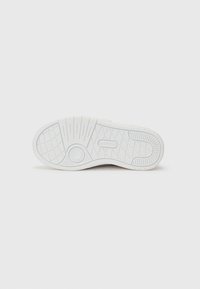 Semelle de sneaker blanche présentant un motif texturé et des rainures pour l'adhérence. Comprend un accent circulaire et un logo de la marque au centre.