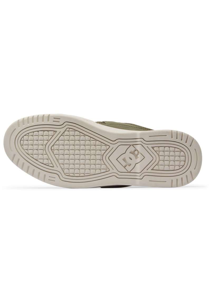 Zapatillas de tela verdes con suela de goma que presenta un patrón de agarre texturizado, detalles de logo y un diseño general de tipo bajo.