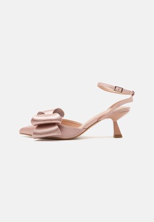 Sapato slingback em cetim cor-de-rosa com bico afunilado, detalhe em laço na parte da frente e uma tira estreita no tornozelo. O salto tem um formato de bloco afunilado.