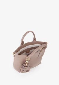 Taupe leren handtas met gouden hardware, dubbele handgrepen en een getextureerd label eraan bevestigd. Het interieur heeft een ritsvak en een zachte voering.