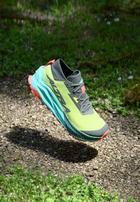 Scarpa da corsa verde lime con una tomaia in rete grigia, suola turchese e dettagli corallo. Presenta un design leggero e ammortizzato per una migliore aderenza.