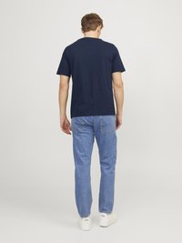 T-shirt en coton marine avec un col rond et des manches courtes, associé à un jean en denim bleu clair et des baskets blanches.