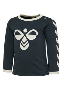 Mörkblå skjorta med lång ärm och gräddvit grafik av en bi och geometriska former. Har gräddvit kant vid halsringning och manschetter, samt mönstrade ärmdekorationer.