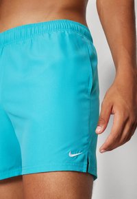 Türkiz színű úszónadrág könnyű szövetből. Rugalmas derékkal, oldalsó hasítékokkal és egy kis fehér Nike logóval az alsó szegélyen.
