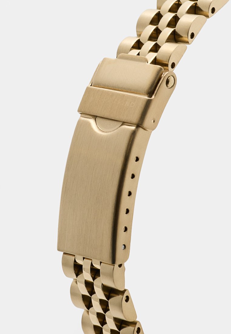 Gouden metalen horlogeband met een geborstelde afwerking, voorzien van een klapsluiting, een verstelbaar schakelontwerp en kleine gaatjes voor maataanpassingen.