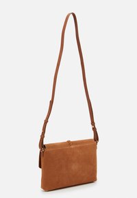 Brązowa zamszowa torba crossbody o prostokątnym kształcie, z regulowanym skórzanym paskiem i górnym zapięciem z plecionym detalem.
