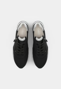 Black sneakers with a textured fabric upper, featuring silver accents, a side zipper, and a lightweight white sole.