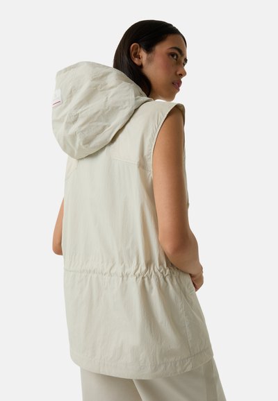 Beige ärmellose Weste mit Kapuze, die eine schmale Taille, eine glatte Textur und subtile Nahtdetails auf der Rückseite aufweist.