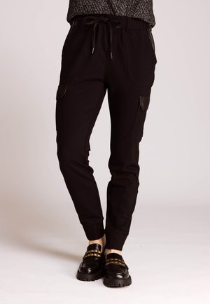Schwarze Jogginghosen mit Cargotaschen, Kordelzug am Bund und gerippten Bündchen; mit Ledereinsätzen und glatter Textur.