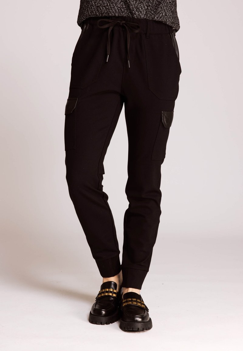 Schwarze Jogginghosen mit Cargotaschen, Kordelzug am Bund und gerippten Bündchen; mit Ledereinsätzen und glatter Textur.