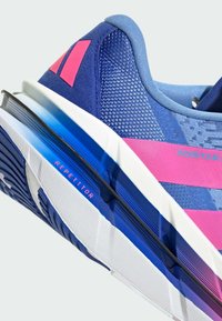 Blauwe sportieve schoen met roze accenten, textuur op de bovenkant en een witte zool met een onderscheidend ontwerp. "Repetitor" merk zichtbaar.