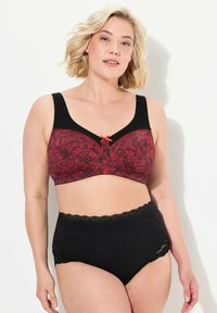 Reggiseno nero e rosso con motivo in pizzo floreale, spalline regolabili e un piccolo fiocco al centro. Slip a vita alta neri con bordo in pizzo.