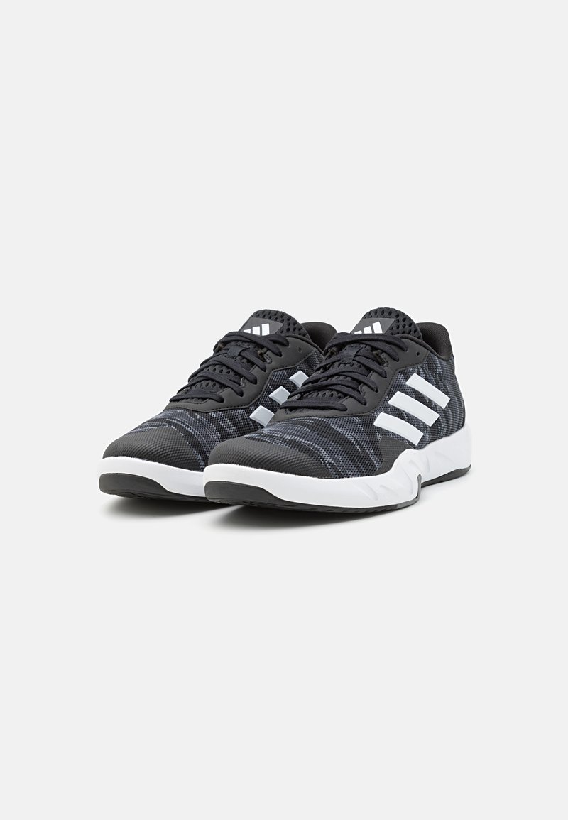 Schwarze Sportschuhe mit einem strukturierten Mesh-Obermaterial, einem weißen Drei-Streifen-Design, gepolstertem Kragen und einer weißen Gummisohle.