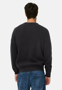 Donkergrijze ribgebreide trui met een ronde hals en lange mouwen, met een relaxte pasvorm en een gestructureerde stof. Draag het met lichtblauwe jeans.